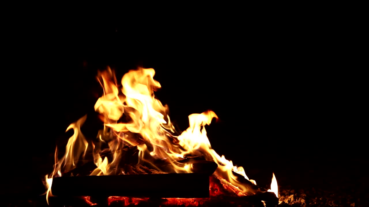 Blazing campfire closeup with glowing flames in pitch dark evening
