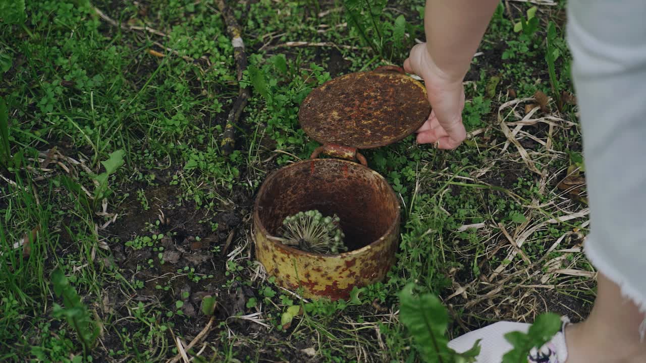 The girl closes the air duct opening on the ground with a metal hatch. Close-up shooting