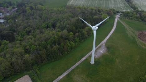 drone shot of a wind turbine next to a green forest