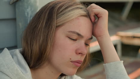 primer plano de una joven en profundo pensamiento, frotando suavemente la frente mientras parece pensativa, su expresión refleja introspección y contemplación, con un fondo borroso