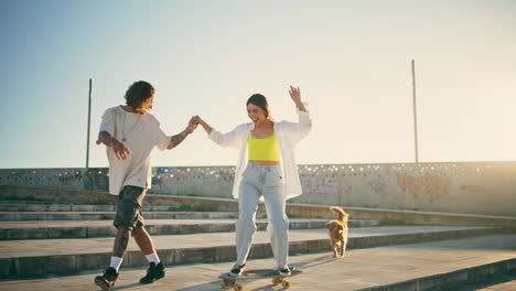 carefree couple riding skate board sunlight stadium. happy woman skateboard ride