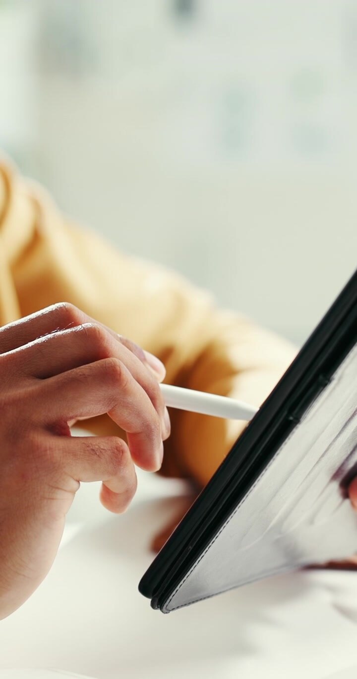 Person Using Stylus Pen on Digital Tablet in Bright Office