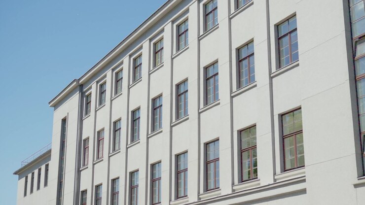 Vista laterale dal basso di un'ampia facciata grigio chiaro con una griglia regolare di finestre di un edificio di istituzione pubblica a Daugavpils, regione di Latgale, Lettonia