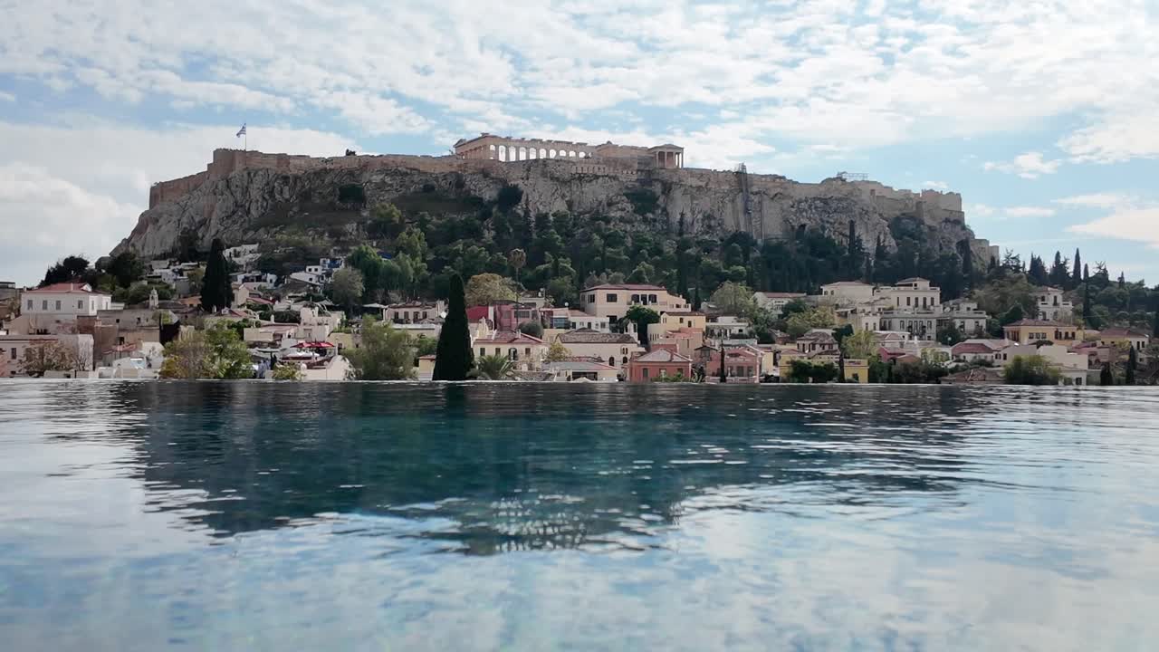 Athens, Beautiful Still frame of Acropolis from a distance over the blue infinity pool under white clouds and blue skies