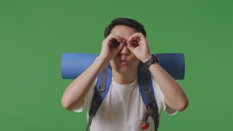 man with backpack looking through hands