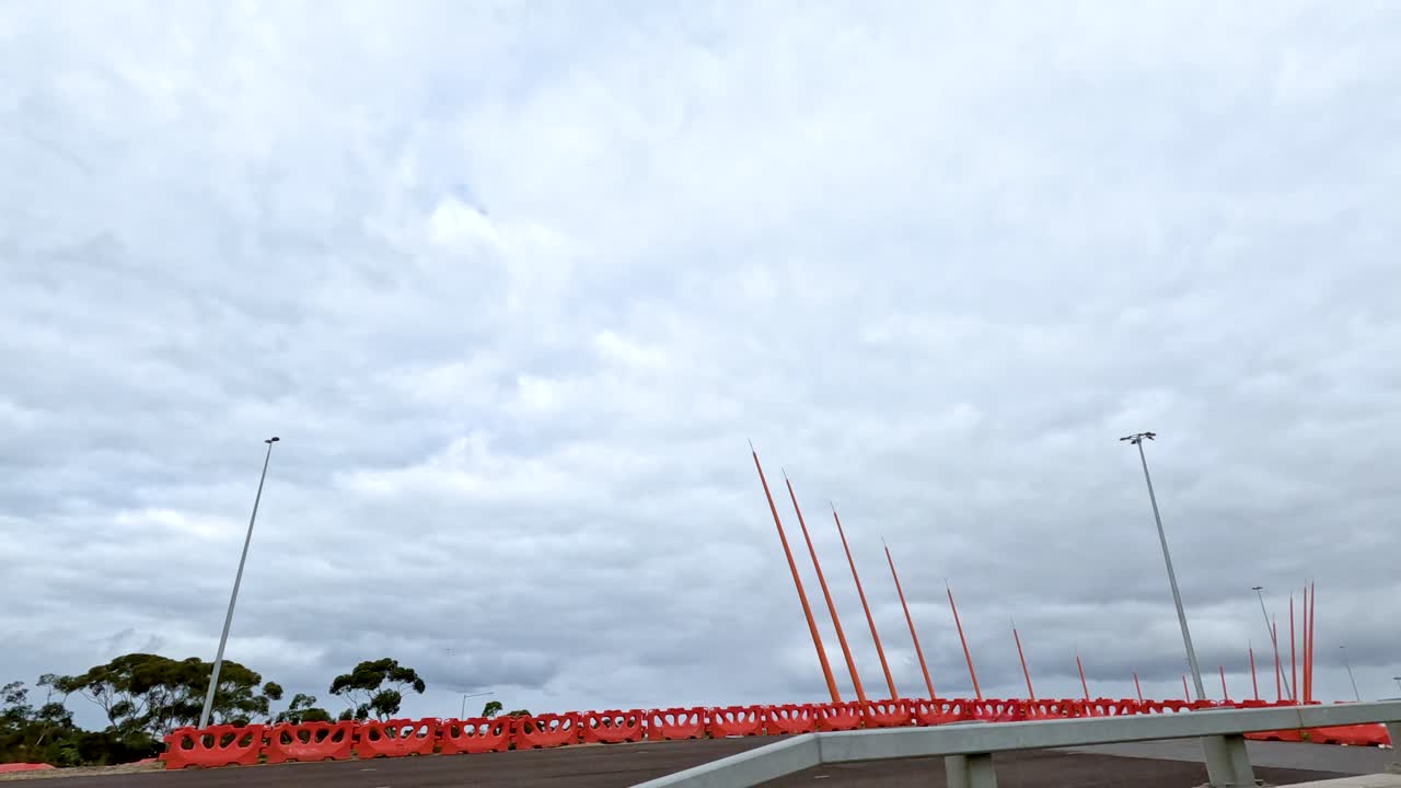 A vehicle moves past red poles on a cloudy day in Melbourne, capturing dynamic motion and urban scenery