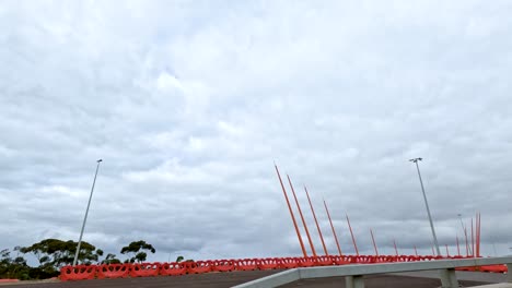 a vehicle moves past red poles on a cloudy day in melbourne, capturing dynamic motion and urban scenery