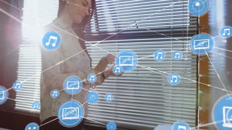 red de iconos digitales contra una mujer de negocios caucásica que usa un teléfono inteligente en la oficina