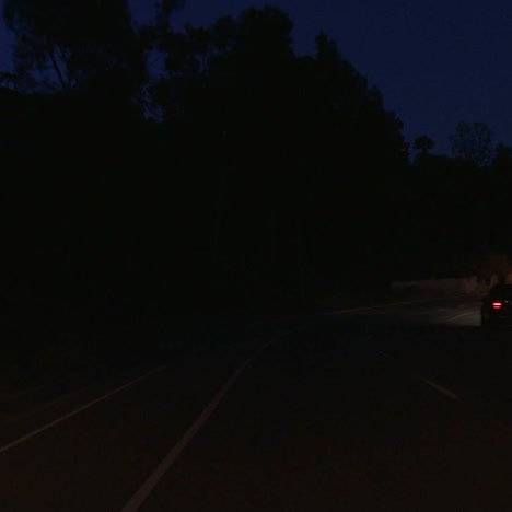 a car travels along a winding street at night in los angeles california as seen through the rear window