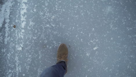 first person view man in boots sliding on frozen pond ice slowmo