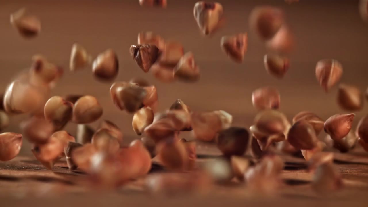 Grani di grano saraceno crudo che cadono al rallentatore su una superficie di legno