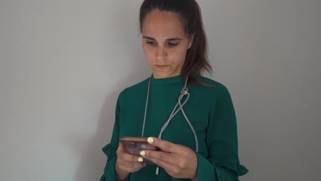 mujer con camisa azul azul mirando hacia abajo mientras usa su teléfono en un entorno interior sencillo