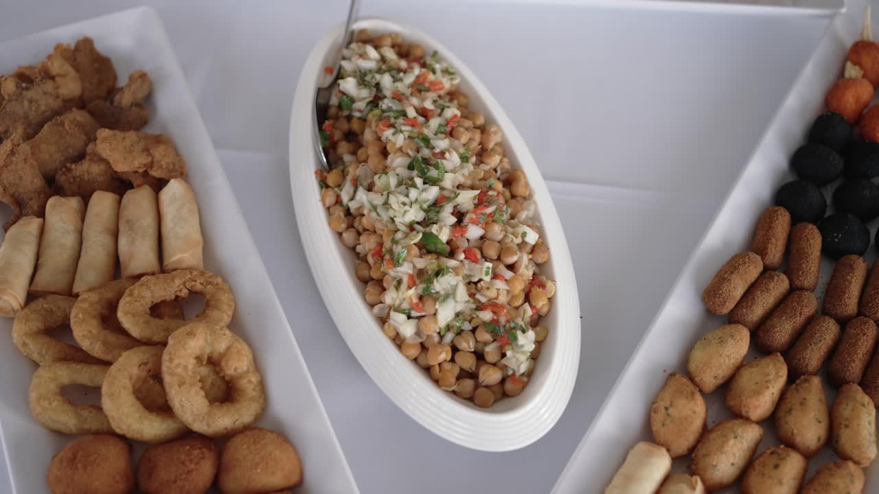 Variety of Portuguese appetizers and chickpea salad served on a white table during a meal