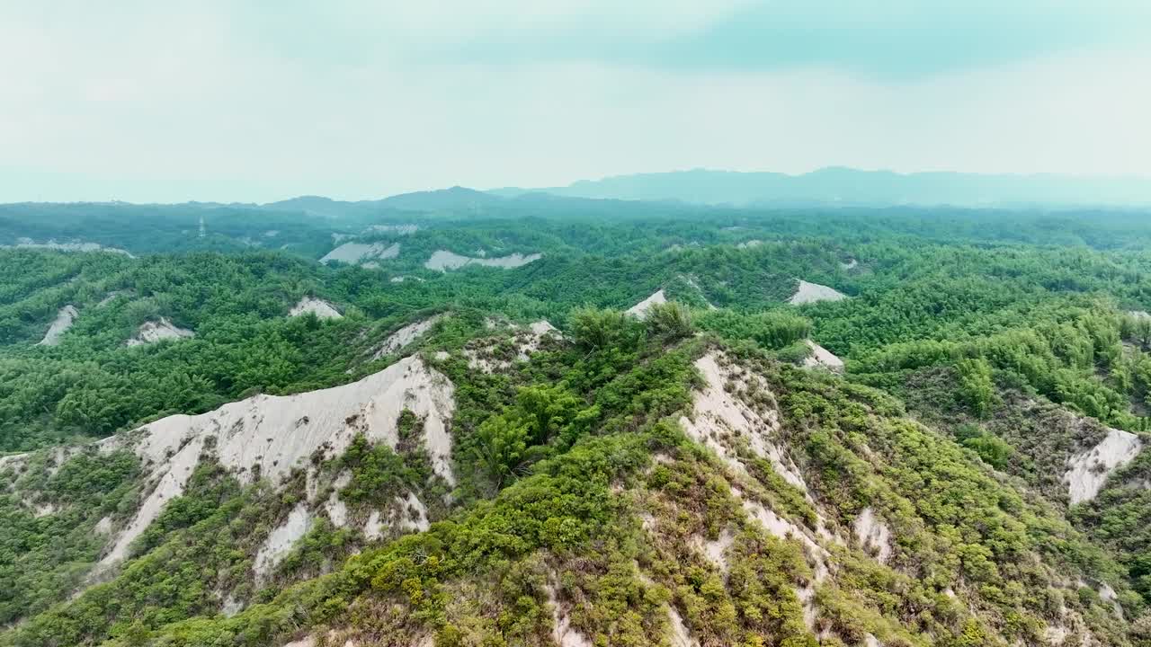 SLow forward flight over greened badlands with moonscape during cloudy day - Taiwan, Tianliao, Kaohsiung