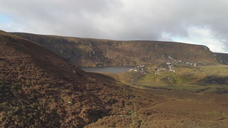 Aerial-of-flyby-of-women-standig-at-lakes-in-epic-stunning-landscape-of-mullaghcleevaun-ireland-with-very-cloudy-sky-hanging-close-depp