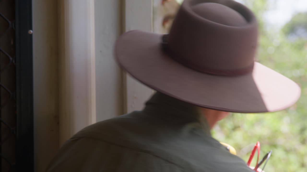Man checks electrical output from a small solar panel installed outside on his country home. Clip 1