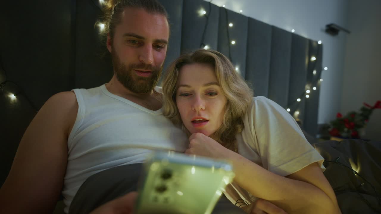 Couple in bed using smartphone