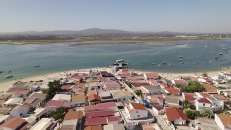 coastal sea town with boats anchored off shore and simple homes of armona island, olhao portugal