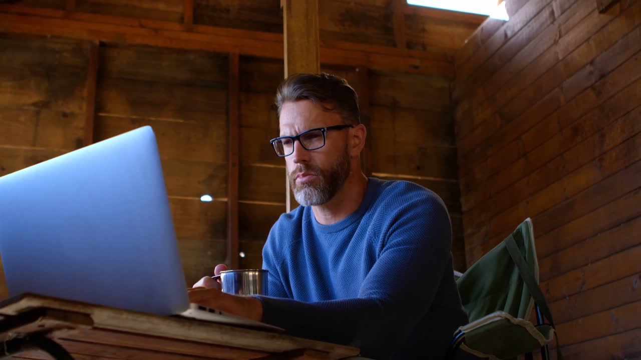 Man having coffee while using laptop while at home 4k