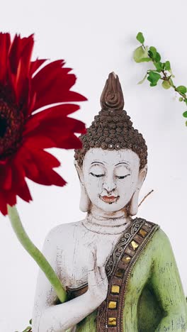 buddha statue with red flower