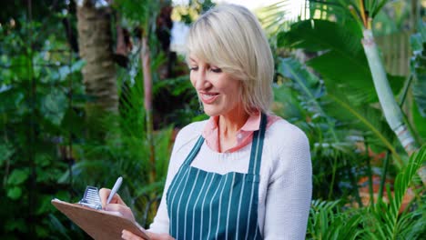 Mature-woman-writing-on-clipboard