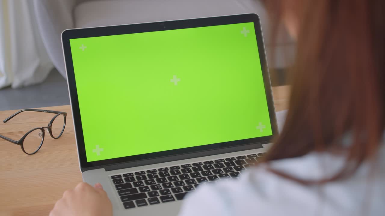 retrato de una joven médica caucásica haciendo una llamada de video en una computadora portátil con pantalla verde en el interior de la oficina