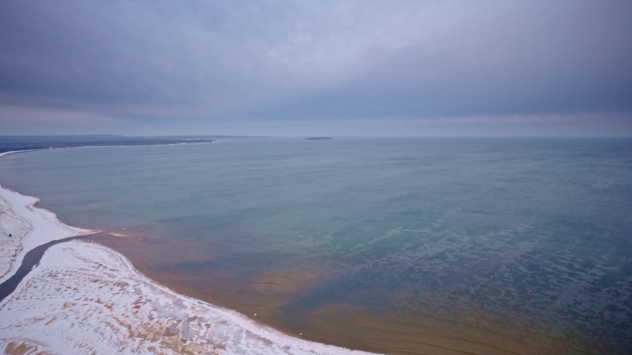 Luftfoto med drone af vinterkysten langs Lake Superior med frosne strande, iset kystlinje, snedækket terræn, fjern vildmark, landskab fra Upper Peninsula og en filmisk vinteratmosfære