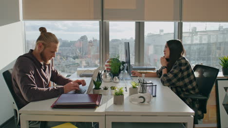 serious colleagues typing computers at workplace close up. man asking woman