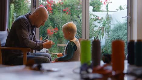 Father-and-son-stitching-keychain-at-home-4k