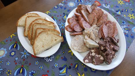 buffet selection of venison sausages on a wooden board with lunch platter of sliced meat and cheese served with rye bread and salad sides