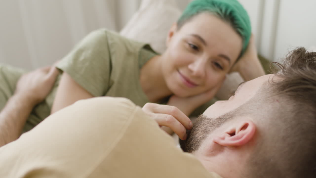 Loving Woman Touching Her Boyfriend's Face While Relaxing On The Bed And Looking At Each Other 1