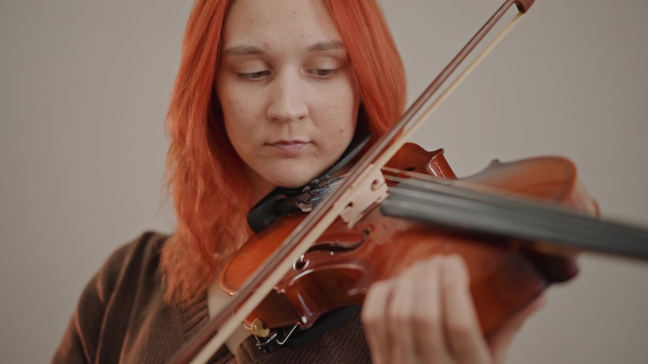 Redhaired violin practice in quiet studio, solo student concentrates with bow and strings closeup fingering, subtle vibrato, focused rehearsal energy and contemporary classical vibe with warm tones
