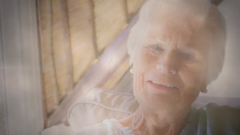 animation of glowing light over portrait of happy senior woman