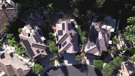 aerial birdseye, over multiple houses, solar panels on roof, in private neighborhood of calabasas