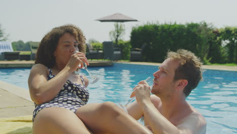 Pareja-Relajándose-En-La-Piscina-Durante-Las-Vacaciones-De-Verano-Celebrando-Bebiendo-Champán