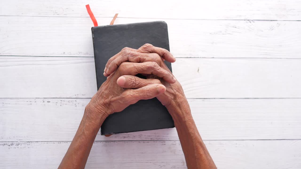 기도하는 손은 열린 성경 위에 있습니다.