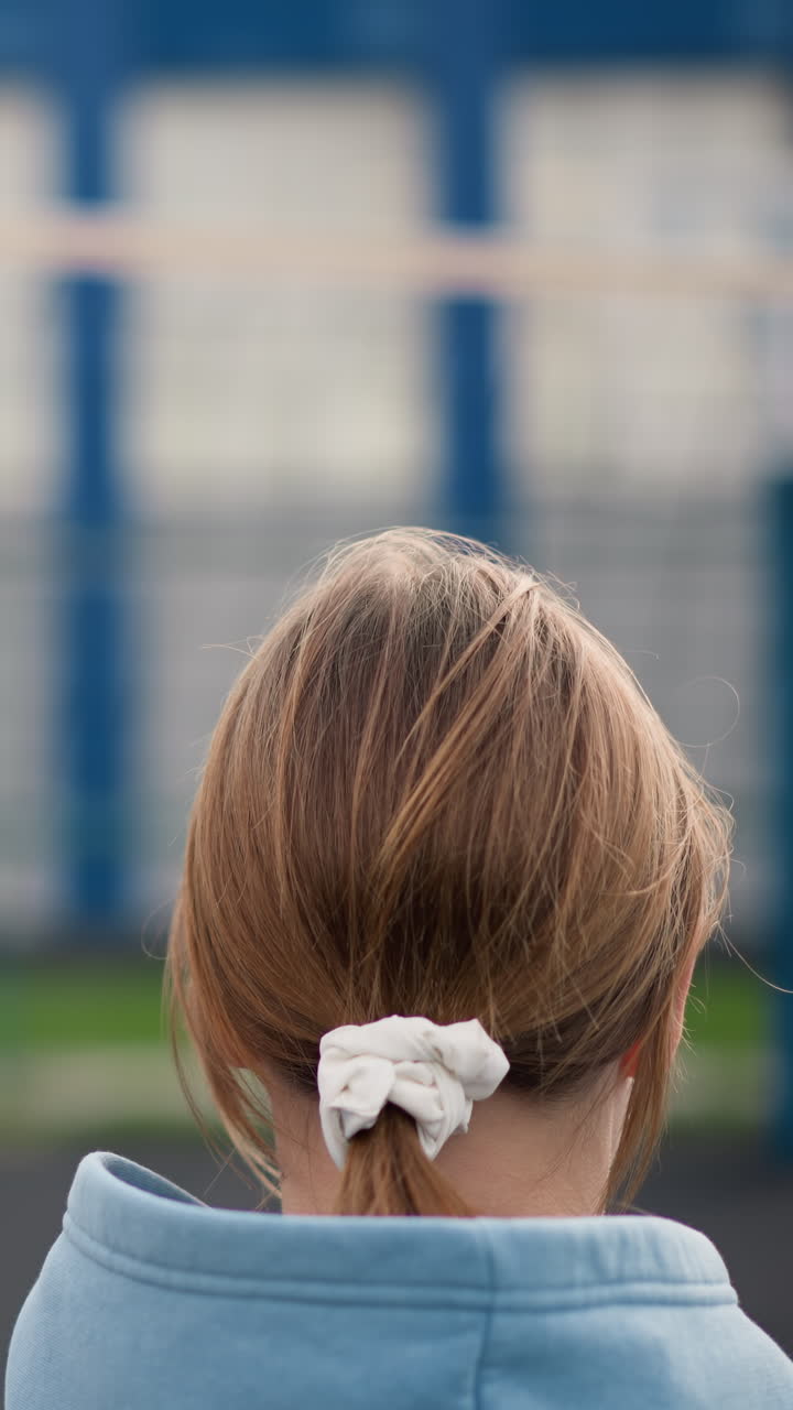 머리카락이 여있는 젊은 여자 배구 선수들의 머리 모습, 검은 리본을 가진 한 명,  리본을 입은 한 명, 코치가 지침을 주고, 강사가 배경에서 움직이는 것을 지켜보고 있습니다.