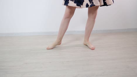 Bare feet on a young and attractive female dancer dancing in a white room