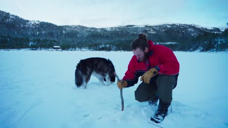 man on snow making hole for ice fishing in winter