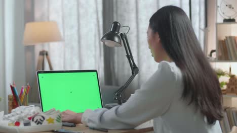 mujer trabajando en una computadora portátil con una pantalla verde