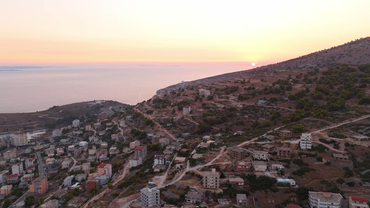 saranda, albania, al atardecer con la costa y los edificios esparcidos en las laderas, vista aérea