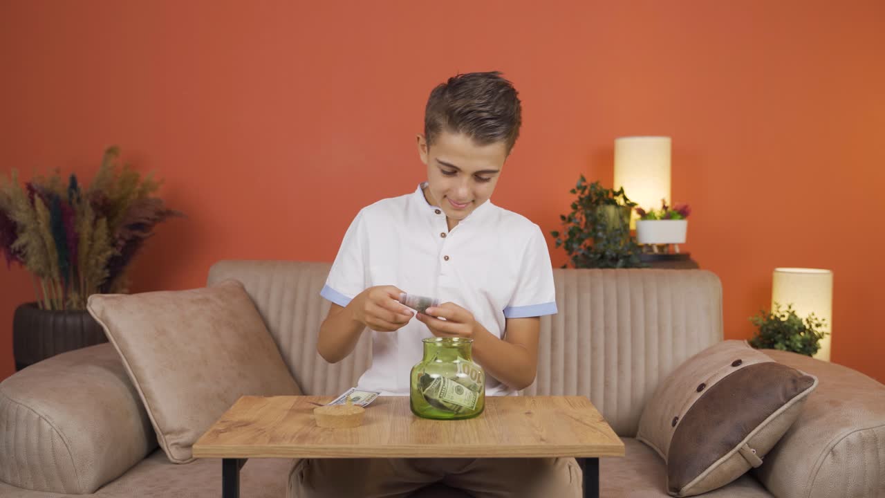 긍정적 인 소년은 돼지 은행에서 돈을 절약합니다.