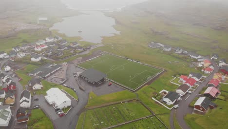 Vista-Aérea-Sobre-Un-Campo-De-Fútbol-En-Un-Pequeño-Pueblo-Cerca-De-Un-Fiordo-En-Las-Islas-Feroe