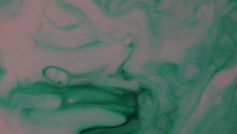 Macro-shot-of-green-ink-moving-in-pink-liquid