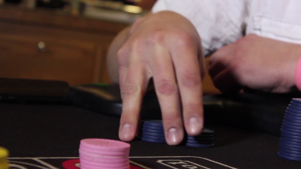 primer plano de una mano masculina inquieta fichas de casino sin marcar en una mesa de juego con movimiento lento de cámara de giro e inclinación
