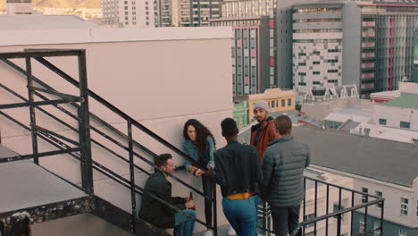 group of friends relaxing on fire escape stairs enjoying rooftop party chatting sharing excitement for weekend celebration in city