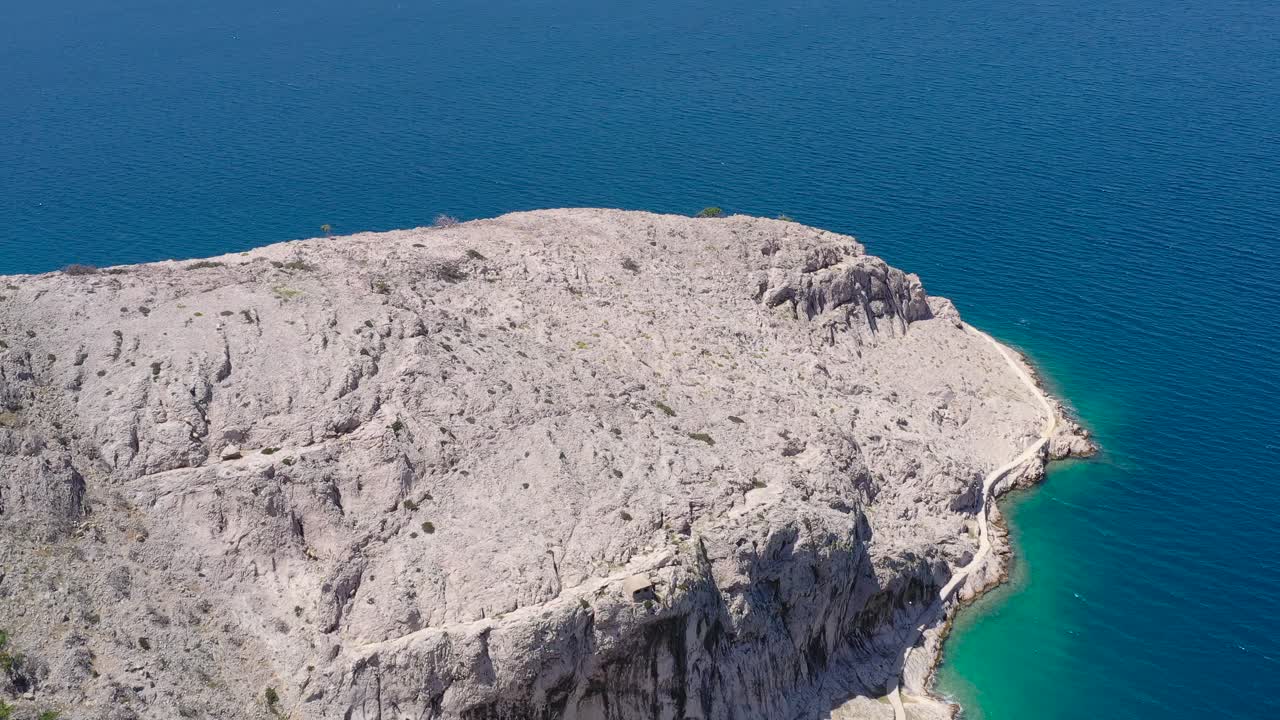 Kip Bogorodice rock at the village of Metajna on Otok Pag island in Croatia with road going around, Aerial flyover view