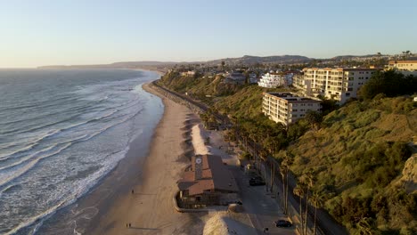 Flying-at-sunset-over-San-Clemente-Pier-Beach,-California,-aerial-wide-slow-motion-spinning-shot