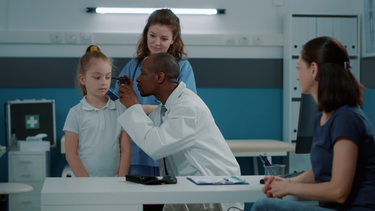 Doctor examining child's ear in clinic