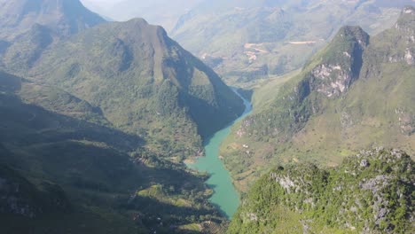 el avión no tripulado se mueve hacia adelante sobre las rocosas montañas cársticas revelando el verde sinuoso río nho que entre las cadenas montañosas ha giang vietnam